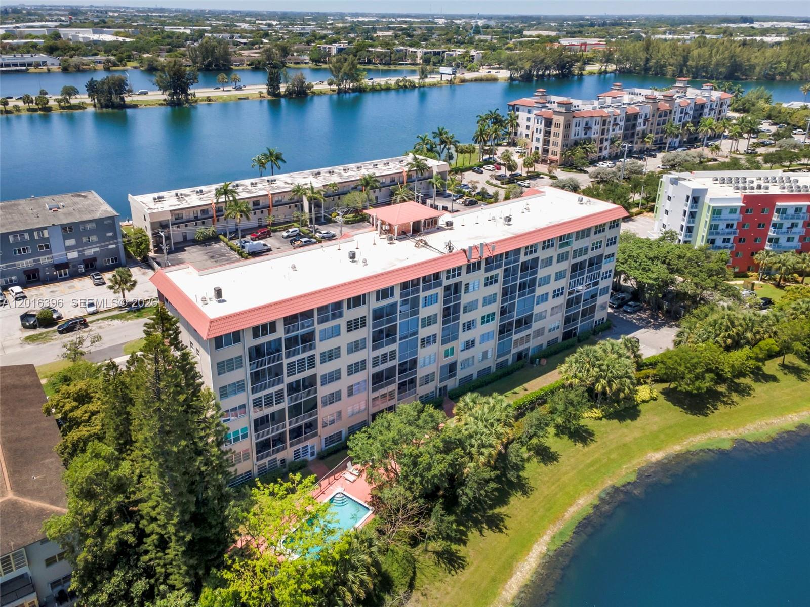 An aerial view shows a multi-story apartment building with a pool next to a lake — 1101 Crystal Lake Dr # 203, Deerfield Beach FL 33064, DEERFIELD BEACH, FL