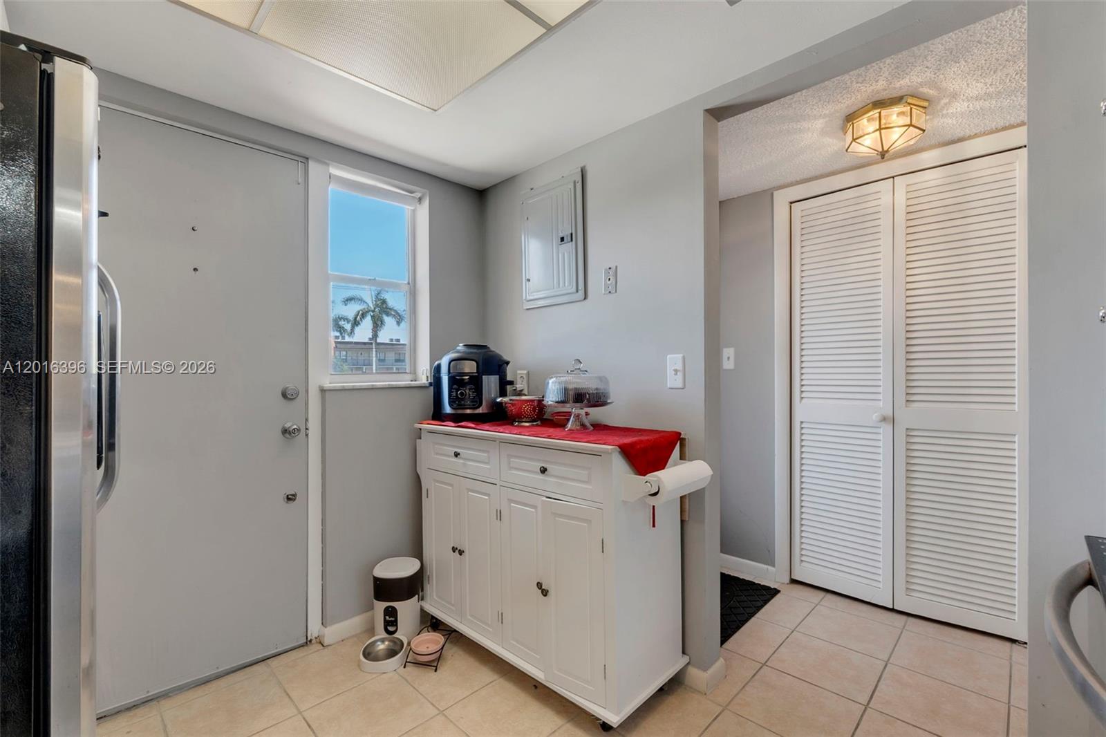 A kitchen area features a white cabinet, a window, and a louvered closet door — 1101 Crystal Lake Dr # 203, Deerfield Beach FL 33064, DEERFIELD BEACH, FL