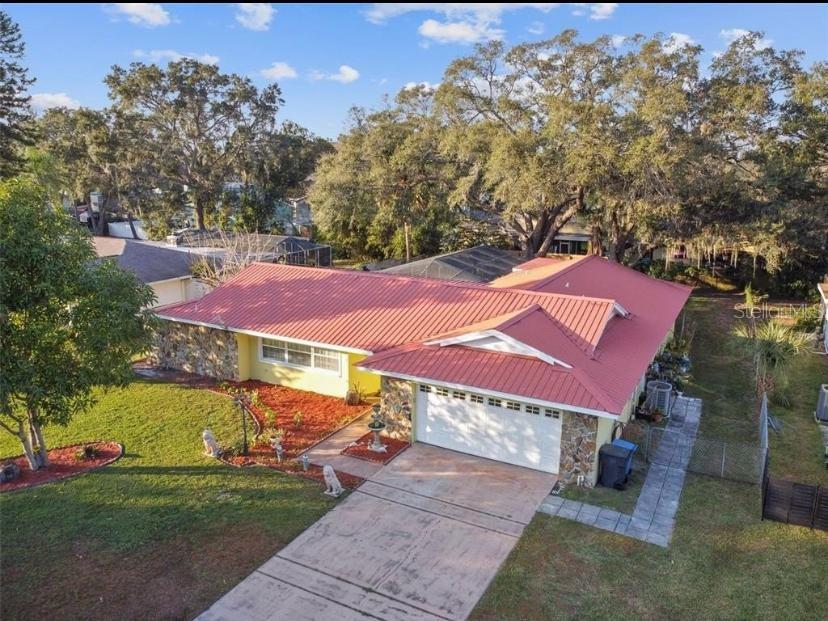 An aerial view of a single-story house with a red metal roof and stone accents — 1514 BURNING TREE LANE, BRANDON, FL