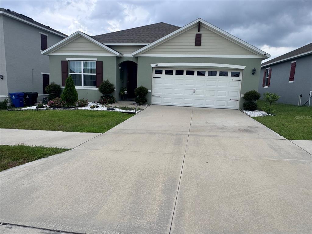 A single-story house with a green stucco exterior, a two-car garage, and a concrete driveway — 641 GRIFFON AVENUE, LAKE ALFRED, FL
