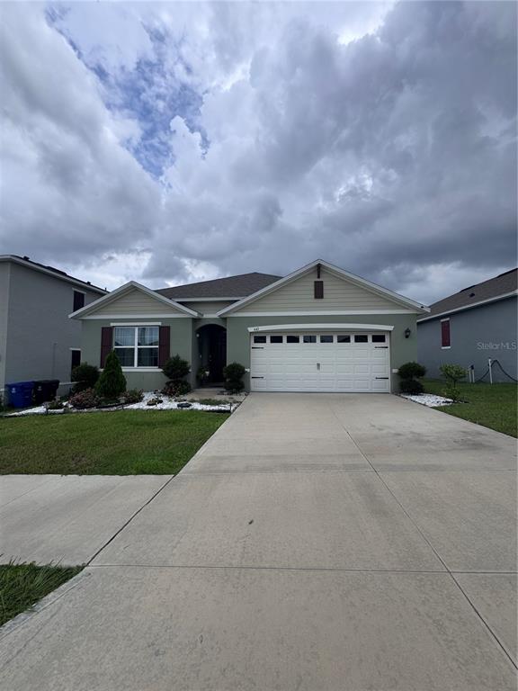 A single-story house with a green exterior, a two-car garage, and a concrete driveway — 641 GRIFFON AVENUE, LAKE ALFRED, FL