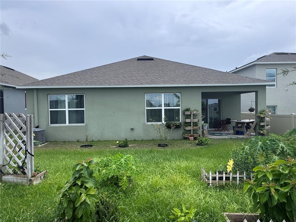 The exterior rear view of a single-story house features a covered patio and green lawn — 641 GRIFFON AVENUE, LAKE ALFRED, FL