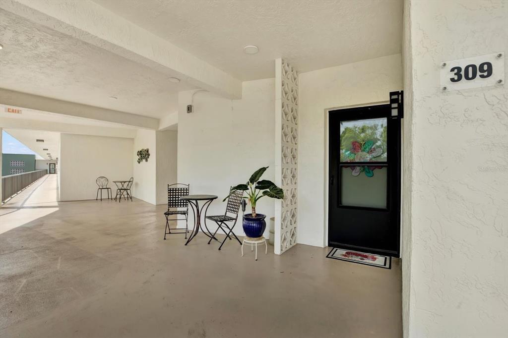An outdoor balcony features a small bistro set, a potted plant, and a front door — 5980 TERRACE PARK DRIVE N UNIT 309, ST PETERSBURG, FL