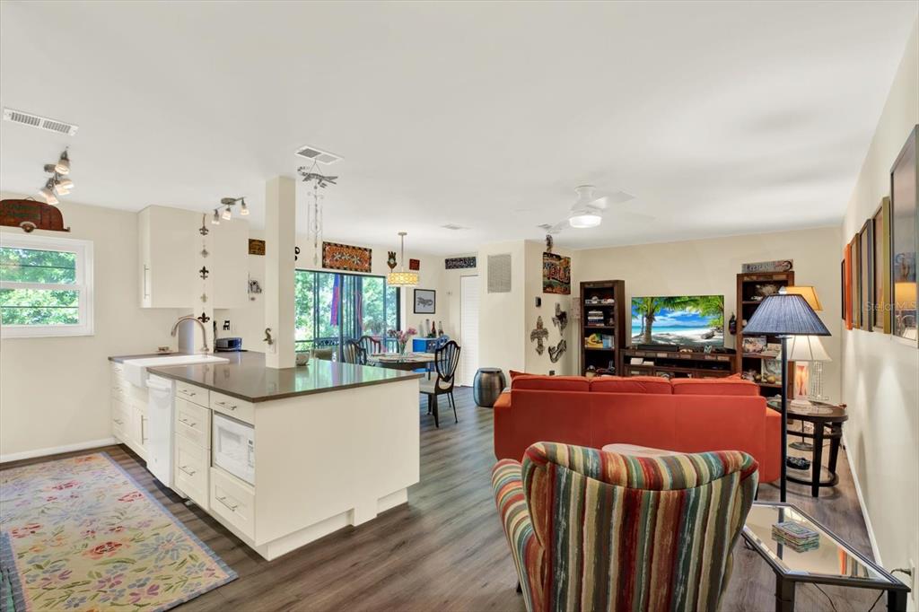 An open-concept living room and kitchen featuring white cabinetry, a kitchen island, and wood-look flooring — 5980 TERRACE PARK DRIVE N UNIT 309, ST PETERSBURG, FL