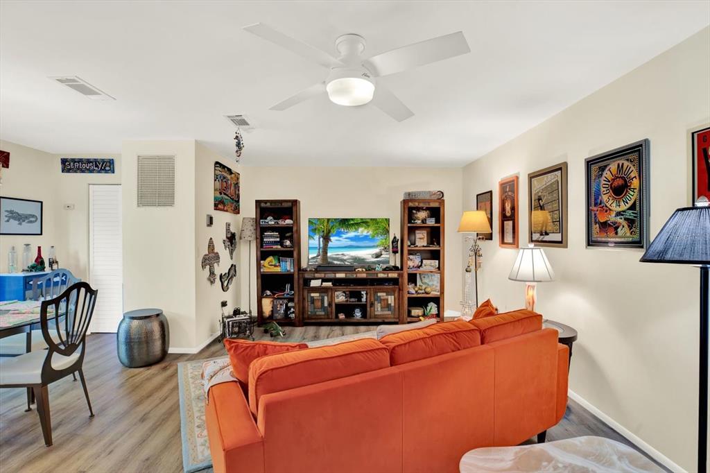 A living room features an orange sofa, a television on a wooden stand, and ceiling fan — 5980 TERRACE PARK DRIVE N UNIT 309, ST PETERSBURG, FL