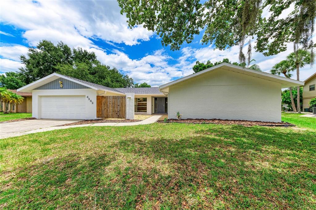A single-story house with a white exterior, a two-car garage, and a wooden privacy fence — 4242 DRYDEN CIRCLE, SARASOTA, FL