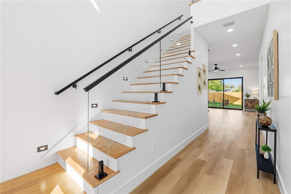 A modern staircase with wooden treads and a glass railing leads to an upper floor — 3531 81ST STREET N, ST PETERSBURG, FL