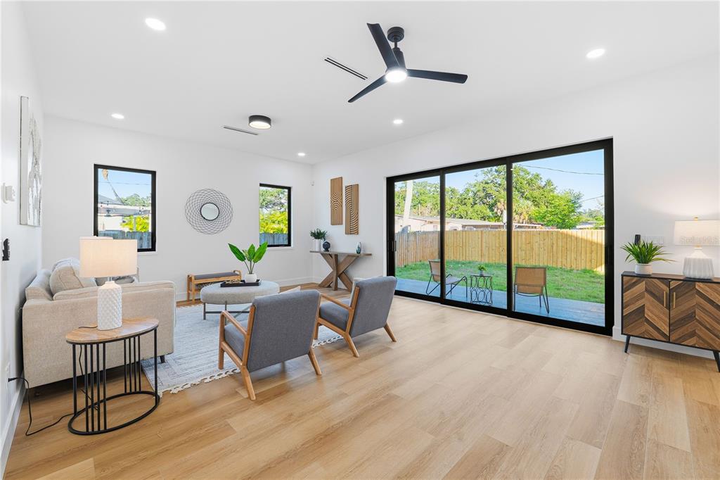 A bright living room features light wood floors, a ceiling fan, and large sliding glass doors — 3531 81ST STREET N, ST PETERSBURG, FL