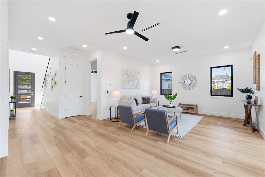 A bright living room features light wood flooring, a ceiling fan, and modern furniture — 3531 81ST STREET N, ST PETERSBURG, FL