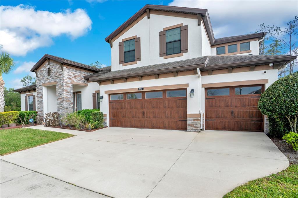 A two-story house with a stone facade, white stucco walls, and a three-car garage — 21914 BUTTERFLY KISS DRIVE, LAND O LAKES, FL