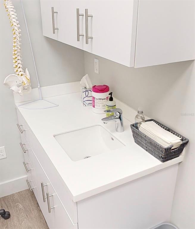 A white bathroom vanity features a sink, faucet, and medical supplies in a clinical setting — 2555 SW 76TH STREET UNIT 110, GAINESVILLE, FL
