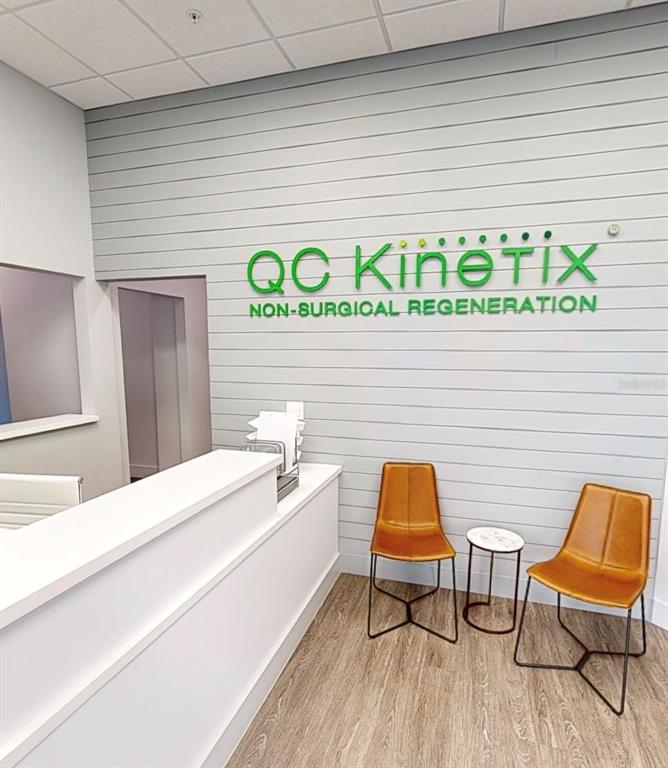 A reception area features a white desk, two tan chairs, and a branded wall sign — 2555 SW 76TH STREET UNIT 110, GAINESVILLE, FL
