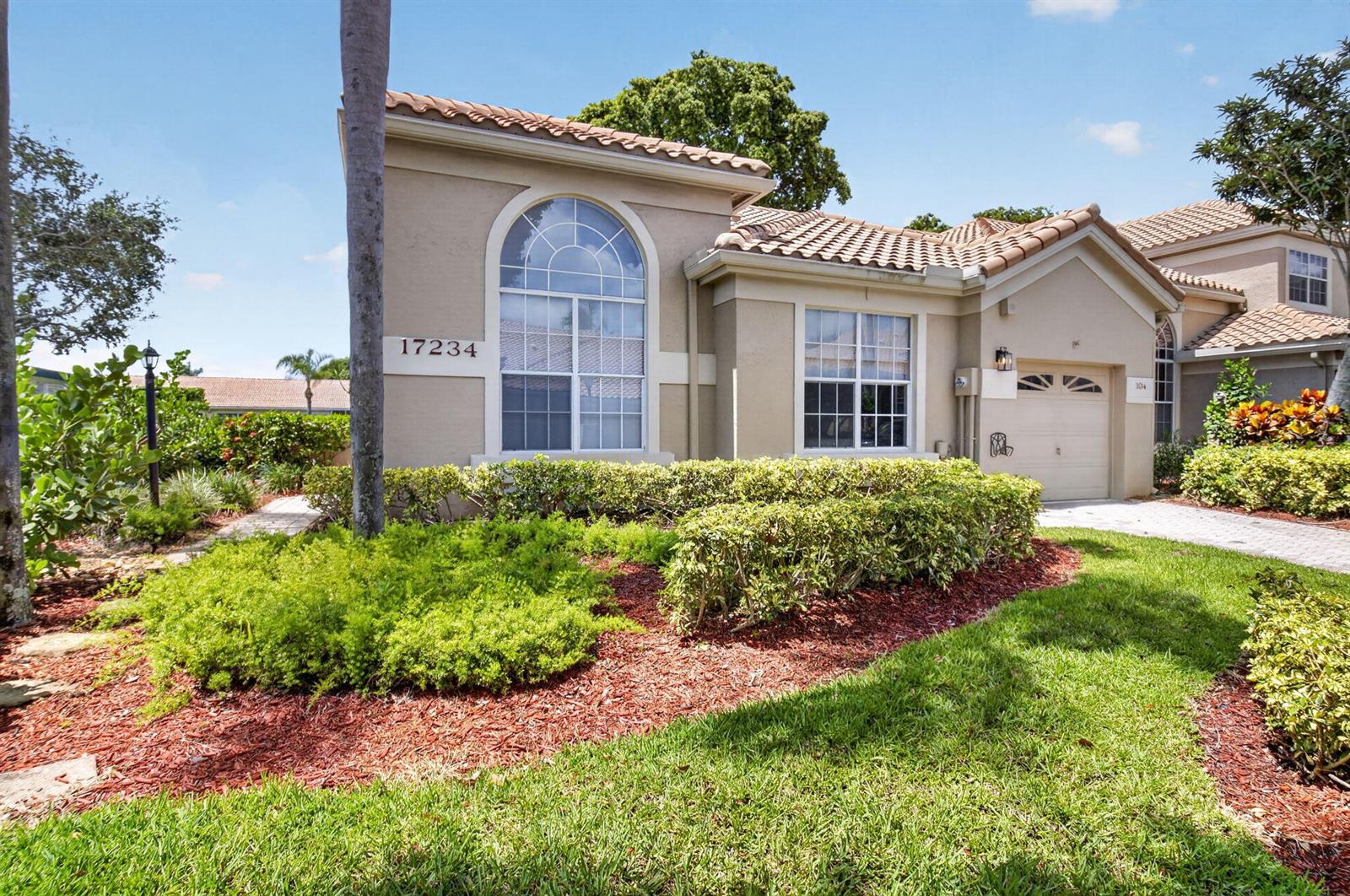 A tan, single-story house with a tile roof, arched window, and attached garage — 17234 Boca Boulevard # 104, Boca Raton FL 33487, BOCA RATON, FL