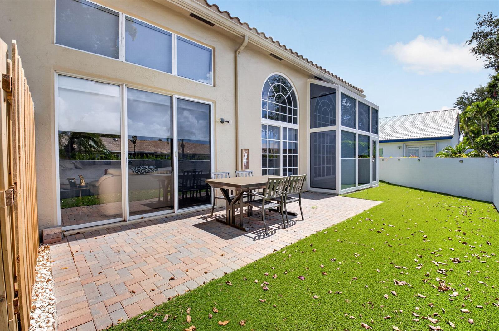 A paved patio with a dining set sits outside a house with sliding glass doors — 17234 Boca Boulevard # 104, Boca Raton FL 33487, BOCA RATON, FL