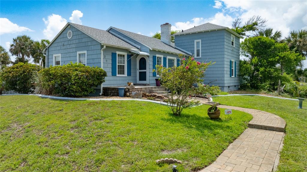 A blue, two-story house with a stone foundation and a paved walkway on a lawn — 2045 S PENINSULA DRIVE, DAYTONA BEACH, FL
