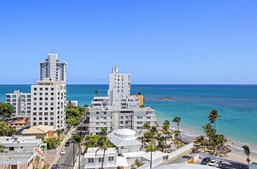 An elevated view of white high-rise buildings along a tropical coastline with blue ocean water — 11 GARDENIA UNIT 1003, CAROLINA, PR