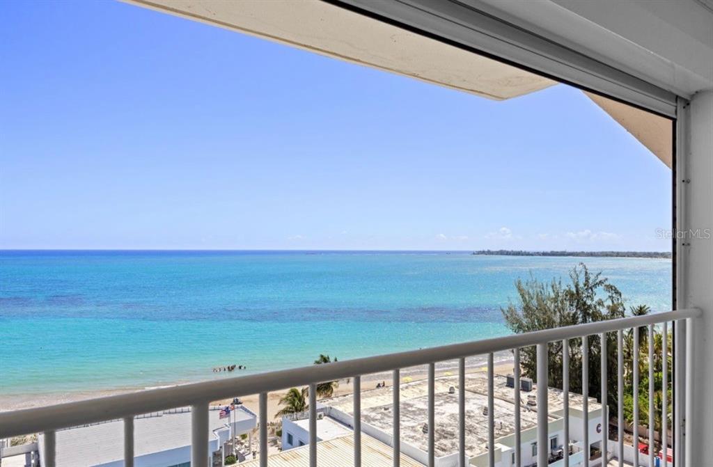 A high-angle view of a beach and ocean from a white-railed balcony — 11 GARDENIA UNIT 1003, CAROLINA, PR