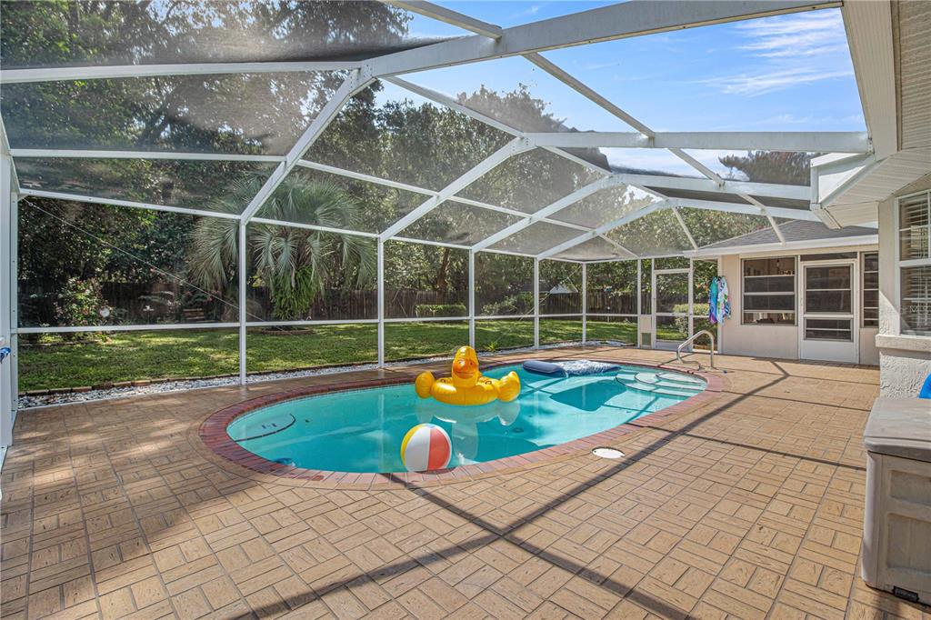 A screened-in swimming pool with a brick paver deck and a grassy backyard — 645 SE 56TH AVENUE, OCALA, FL
