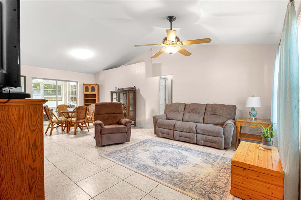 A living room features tile flooring, a ceiling fan, a sofa, and a recliner — 645 SE 56TH AVENUE, OCALA, FL