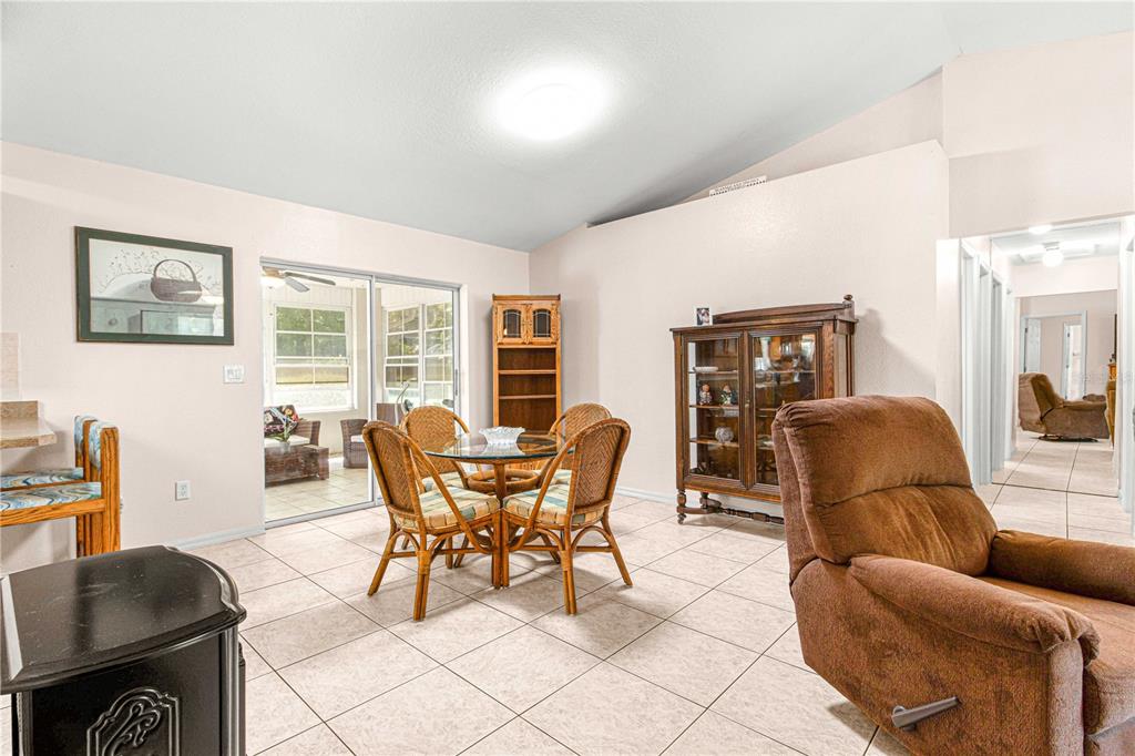 A dining area with a glass table and wicker chairs sits near a sliding glass door — 645 SE 56TH AVENUE, OCALA, FL