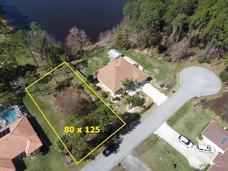 An aerial view shows a vacant residential lot outlined in yellow next to a house — 3 KALORAMA COURT, PALM COAST, FL