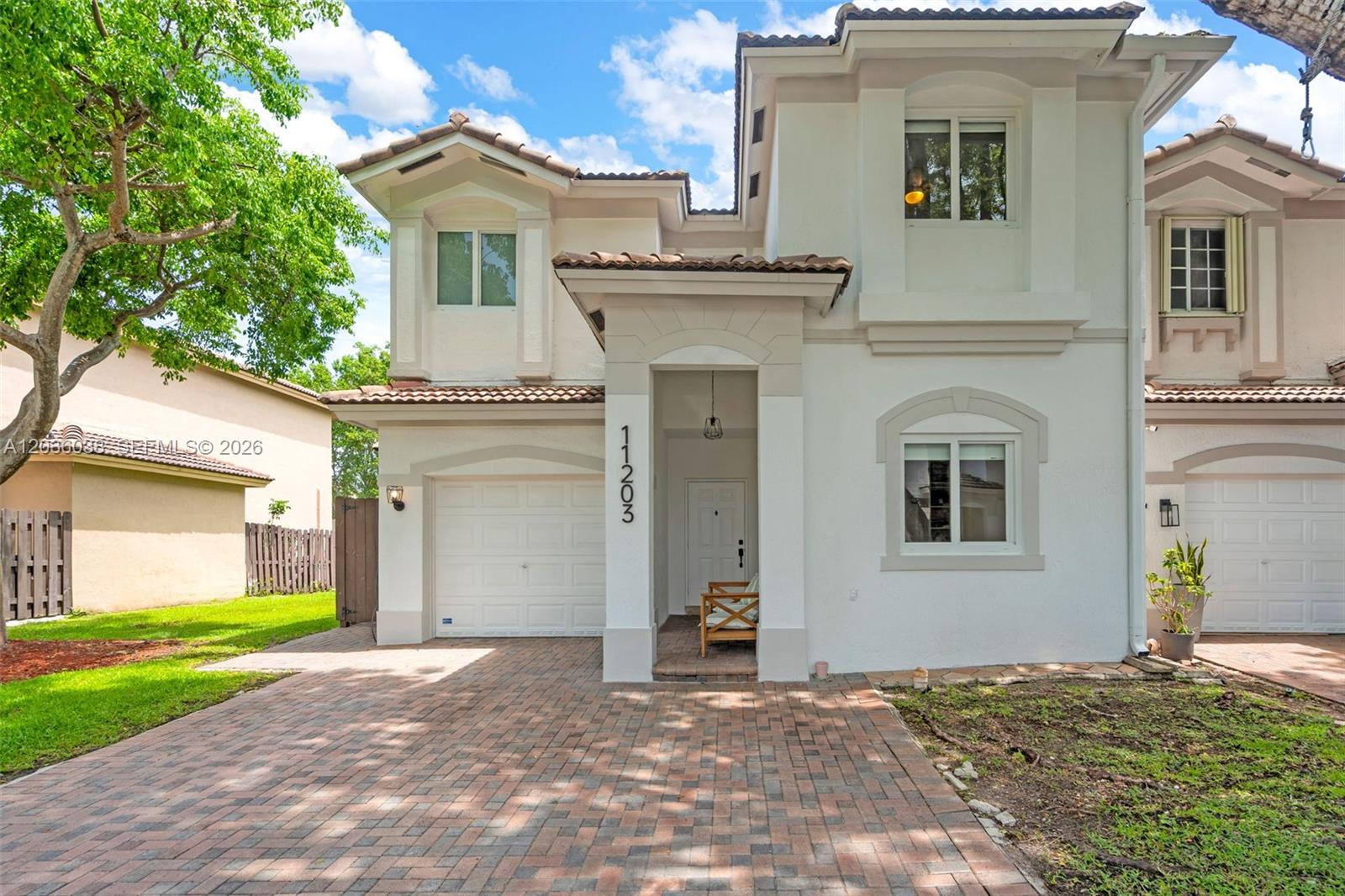 A two-story stucco house features a brick driveway, a single-car garage, and a covered entryway — 11203 NW 73rd Ter, Doral FL 33178, DORAL, FL
