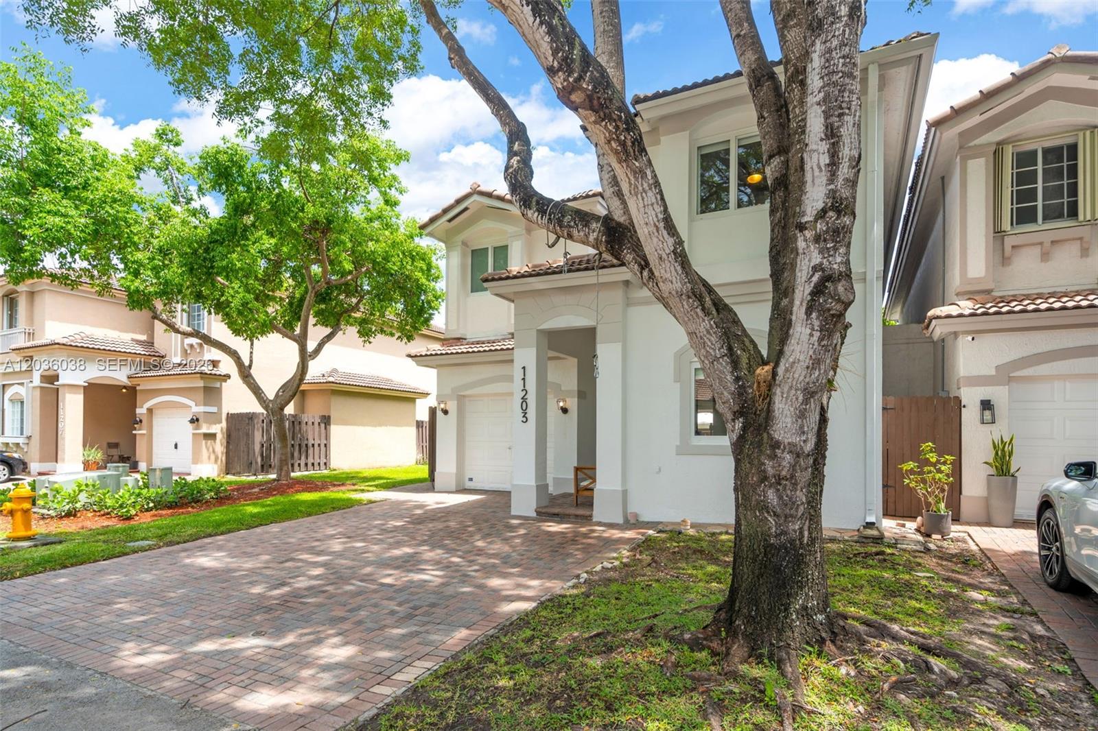 A two-story house with a brick driveway, a large tree, and a white garage door — 11203 NW 73rd Ter, Doral FL 33178, DORAL, FL