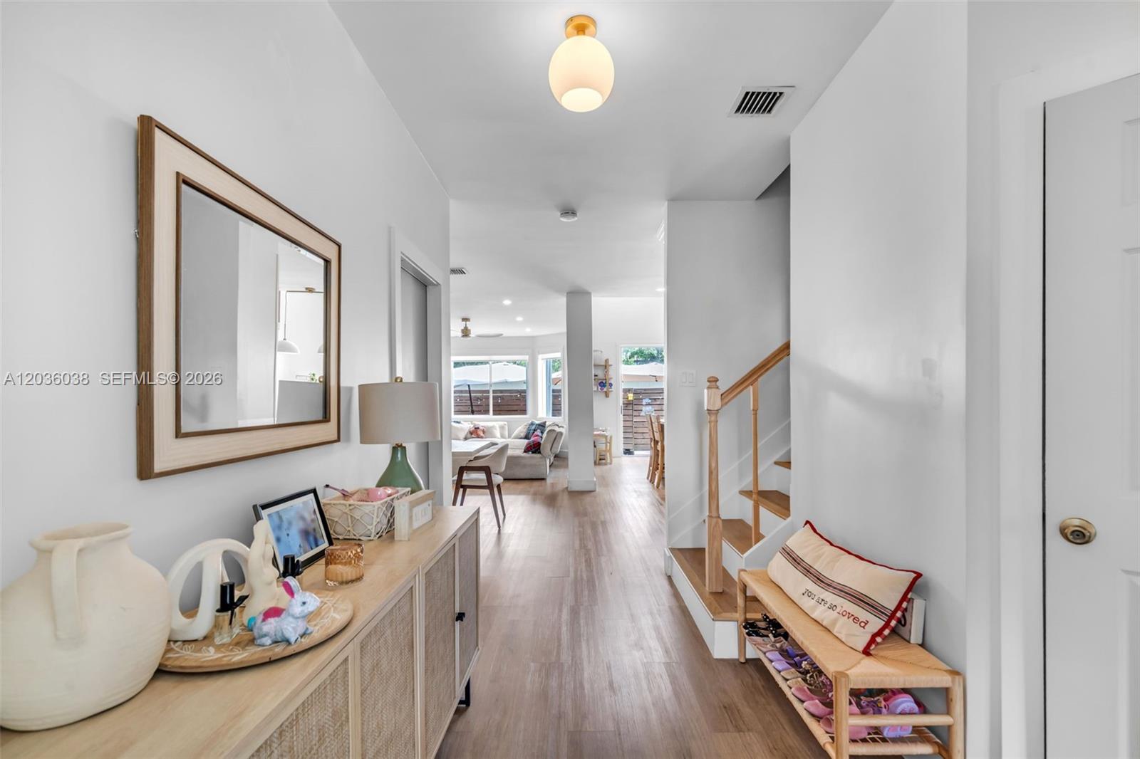 A bright entryway features a wooden console table, a staircase, and a view into the living area — 11203 NW 73rd Ter, Doral FL 33178, DORAL, FL