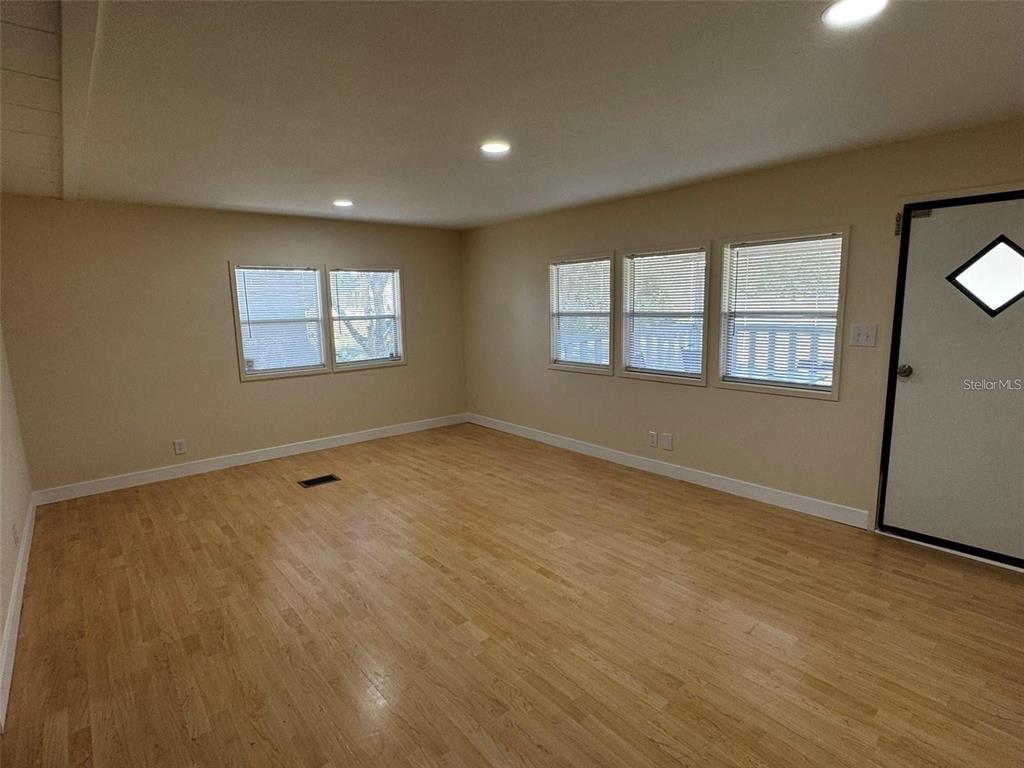 An empty room features light wood flooring, white walls, recessed lighting, and several windows — 15516 LARKSPUR STREET, ORLANDO, FL