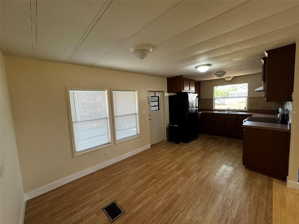A kitchen and dining area feature wood-look flooring, light walls, and dark wood cabinetry — 15516 LARKSPUR STREET, ORLANDO, FL