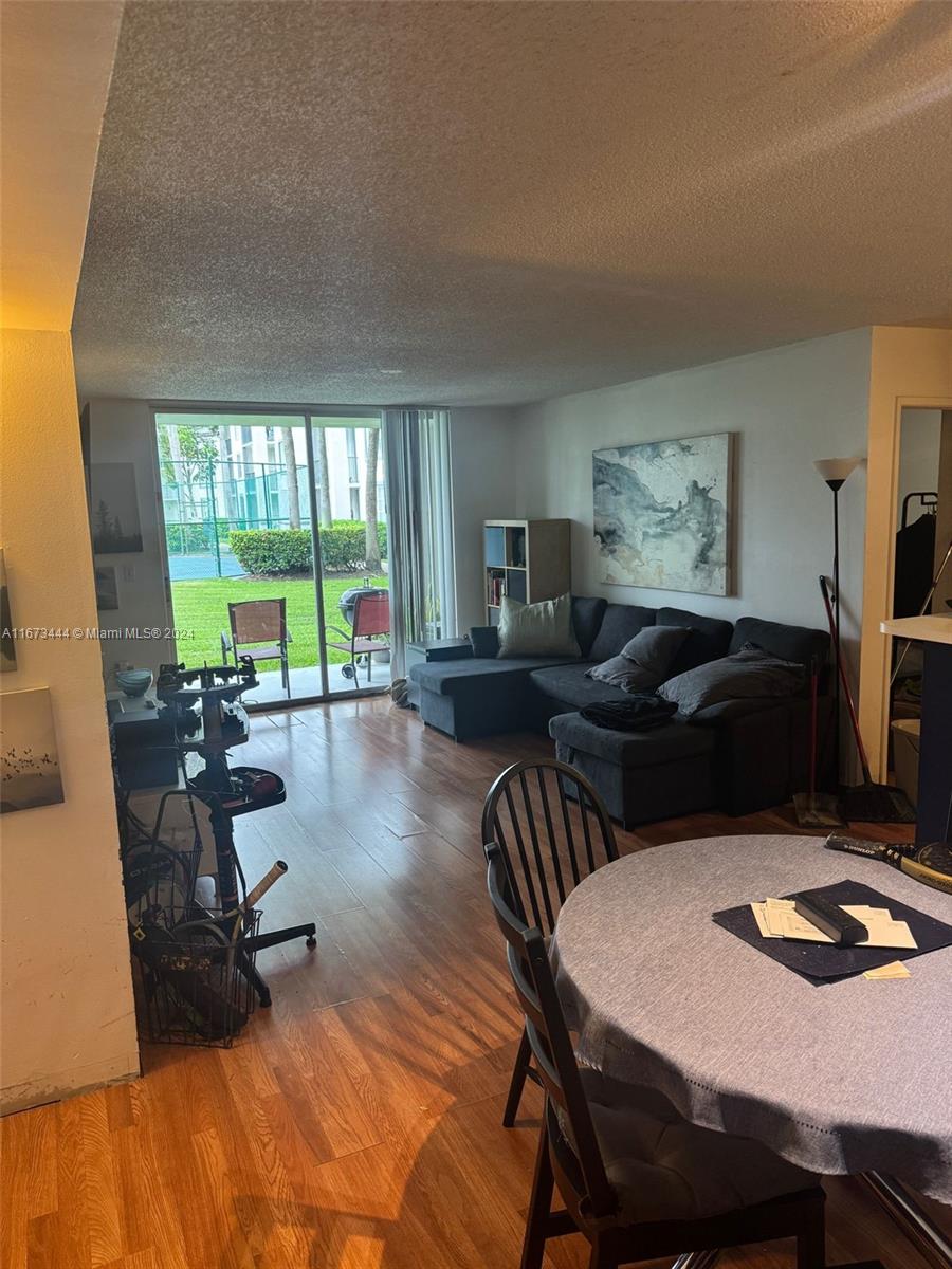 A living room features wood-look flooring, a sectional sofa, and a sliding door to a patio — 4580 NW 107th Ave # 13, Doral FL 33178, DORAL, FL