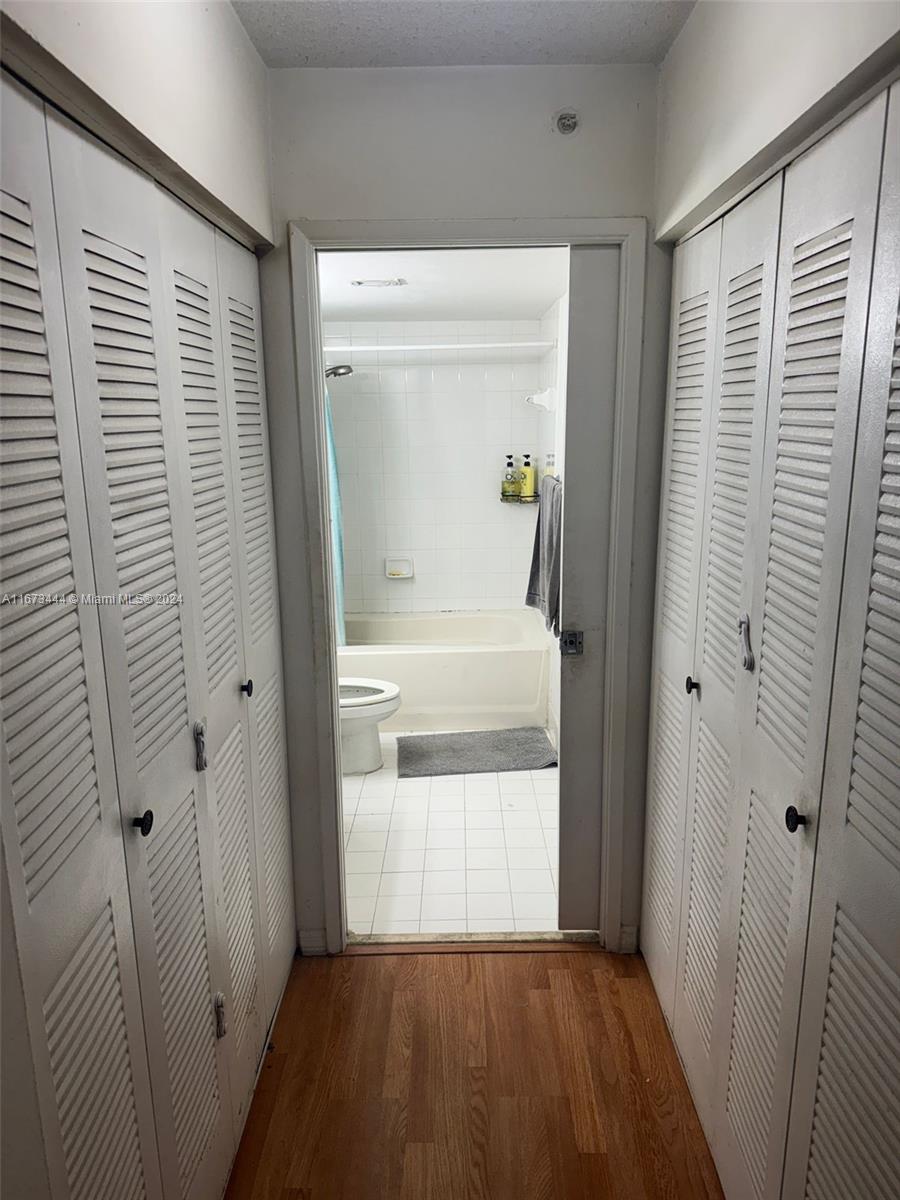 A hallway with louvered closet doors leads into a bathroom featuring a tub and shower — 4580 NW 107th Ave # 13, Doral FL 33178, DORAL, FL