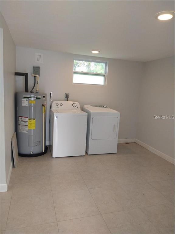 A laundry room features a water heater, a washing machine, and a dryer on tile flooring — 2155 TEMPLE STREET, SARASOTA, FL