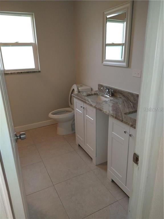 A bathroom features a white vanity with a stone countertop, a toilet, and a window — 2155 TEMPLE STREET, SARASOTA, FL