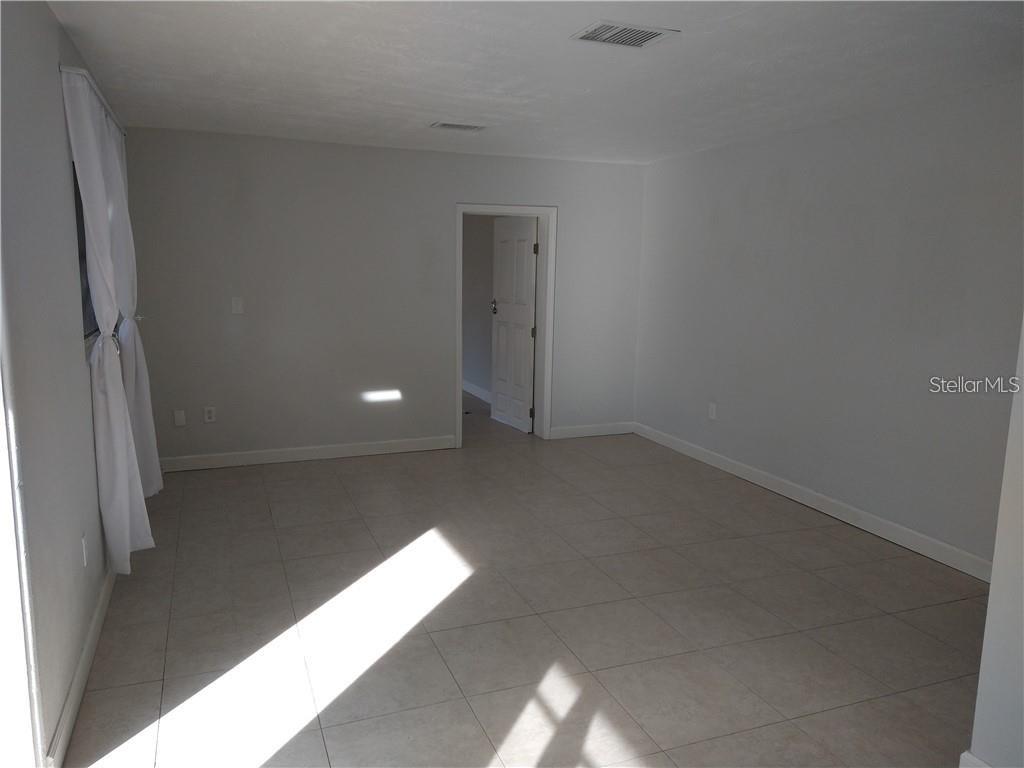 An empty room with light-colored tile flooring, white walls, and a doorway leading elsewhere — 2155 TEMPLE STREET, SARASOTA, FL