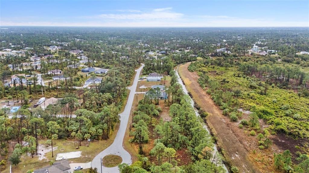 An aerial view shows a residential street with scattered houses surrounded by dense pine forests — Lot 29 GOURMET ROAD, NORTH PORT, FL