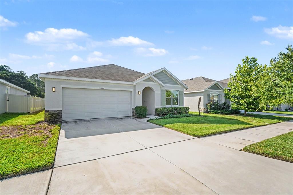 A single-story suburban house features a two-car garage, a concrete driveway, and a grassy lawn — 10792 QUAIL GROVE WAY, SAN ANTONIO, FL