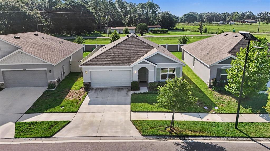 An aerial view shows three suburban houses with driveways, lawns, and a shared fence line — 10792 QUAIL GROVE WAY, SAN ANTONIO, FL