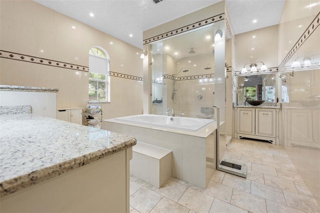 A spacious bathroom features a central soaking tub, a glass-enclosed shower, and dual vanity cabinets — 7393 ROYAL OAK DRIVE, SPRING HILL, FL