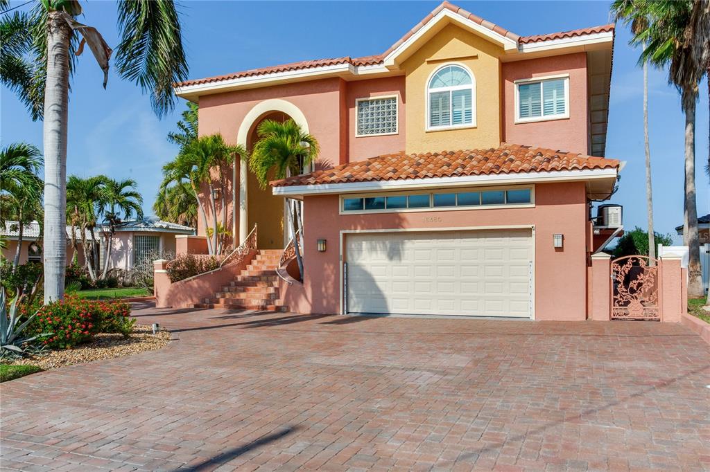 A two-story peach-colored house with a tiled roof, a garage, and a brick driveway — 16480 REDINGTON DRIVE, REDINGTON BEACH, FL