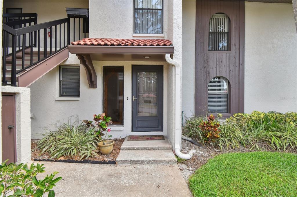 The exterior of a multi-story residential building features a front door, stairs, and landscaping — 3505 TARPON WOODS BOULEVARD UNIT P404, PALM HARBOR, FL