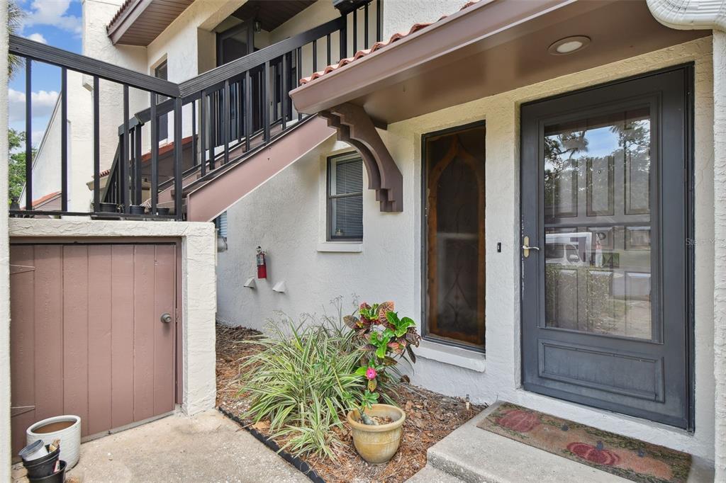 The exterior entrance features a dark storm door, a small garden bed, and a wooden staircase — 3505 TARPON WOODS BOULEVARD UNIT P404, PALM HARBOR, FL