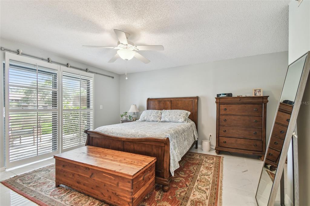 A bedroom features a wooden bed, a matching dresser, a cedar chest, and sliding glass doors — 3505 TARPON WOODS BOULEVARD UNIT P404, PALM HARBOR, FL