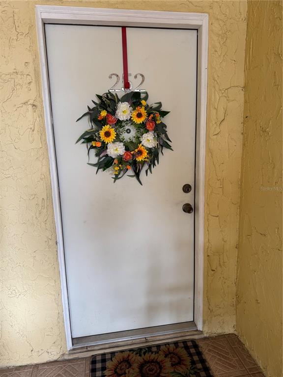 A white front door with a sunflower wreath and the number 252 hangs on it — 3453 CLARK UNIT 252, SARASOTA, FL