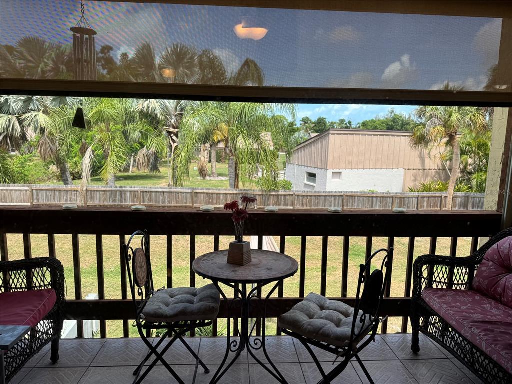 A covered balcony features a small bistro table, two chairs, and a view of palm trees — 3453 CLARK UNIT 252, SARASOTA, FL