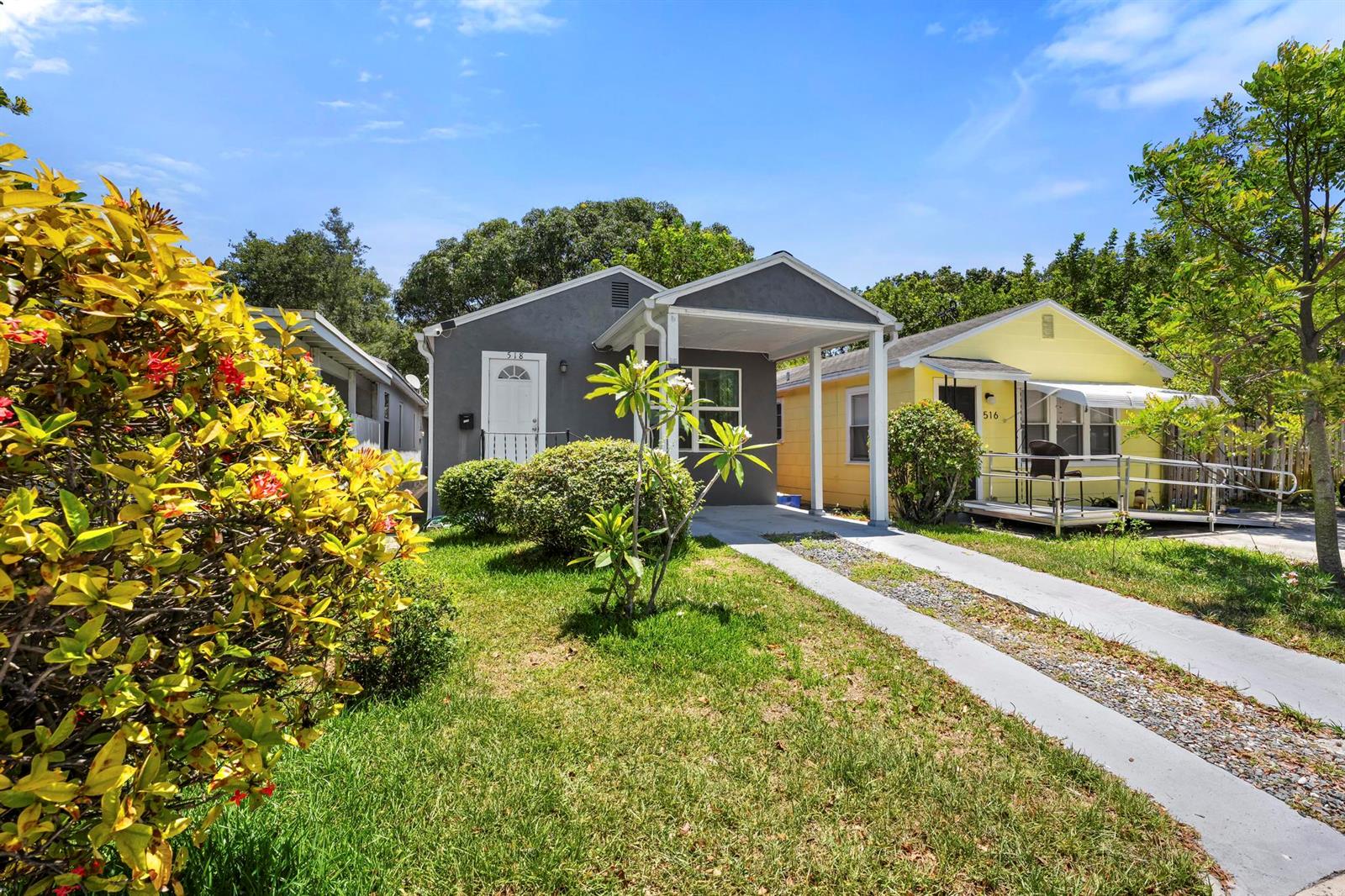 A gray house with a carport sits next to a yellow house with a ramp — 518 N C Street, FL 33460, FL