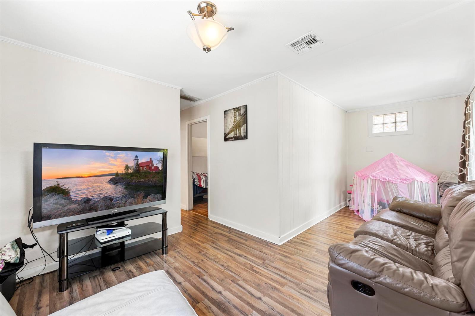 A living room features wood-look flooring, a television on a stand, and a pink play tent — 518 N C Street, FL 33460, FL