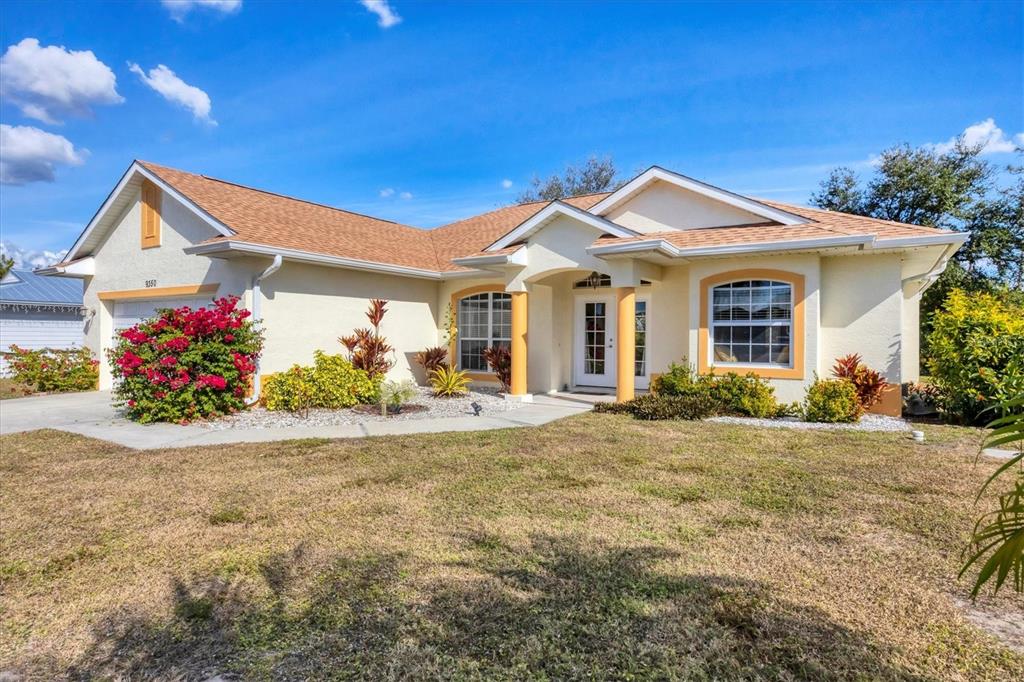 A single-story house with a beige stucco exterior, orange trim, and a brown shingled roof — 9350 GULFSTREAM BOULEVARD, ENGLEWOOD, FL
