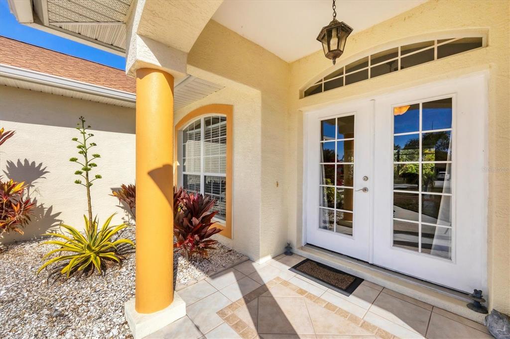 A covered entryway features a tiled porch, a yellow column, and white double glass doors — 9350 GULFSTREAM BOULEVARD, ENGLEWOOD, FL