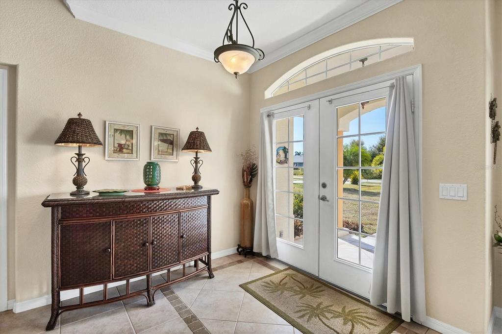 An entryway features a wicker console table, two lamps, and double glass doors with curtains — 9350 GULFSTREAM BOULEVARD, ENGLEWOOD, FL